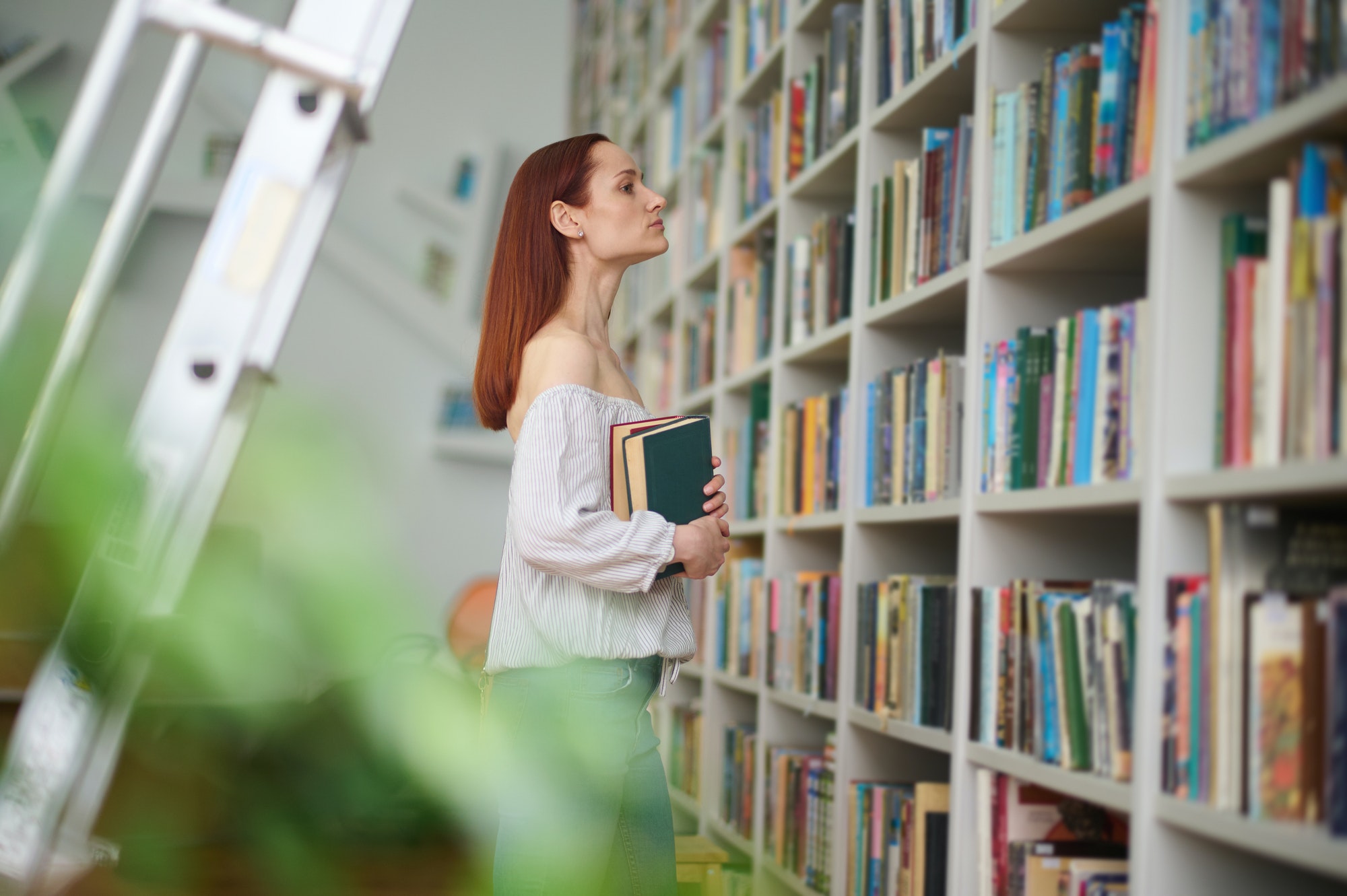 Profile of woman with books near bookshelves